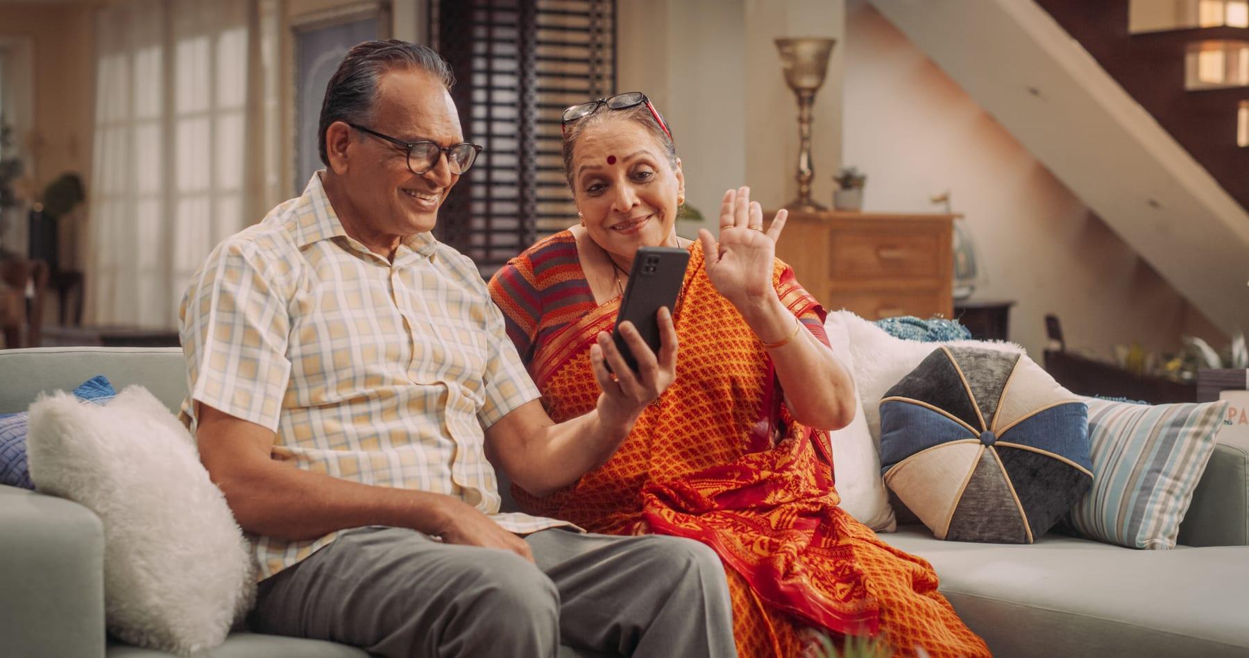 An elderly couple smiling at a video call on a phone